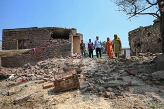 Indian villagers stand near a house damaged by overnight Pakistani artillery shelling in Pahari Wala village near the Line of Control (LoC) in India's Jammu region on May 11, 2025.